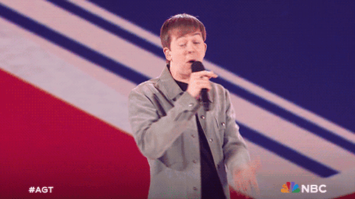 Man Singing Into Microphone With NBC Logo