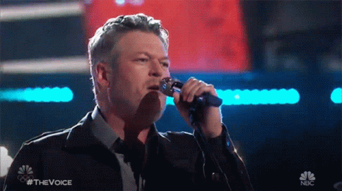 Man Singing Into Microphone With NBC Logo