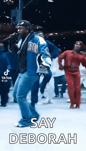 Man Singing Into Microphone With People Dancing Behind