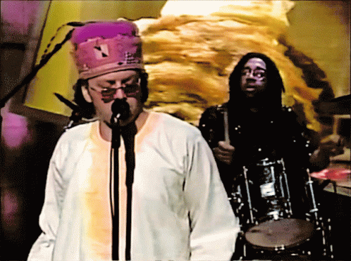 Man Singing Into Microphone With Purple Hat
