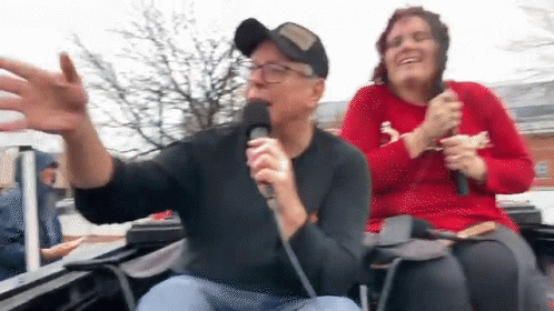 Man Singing Into Microphone With Woman Behind