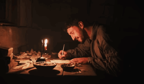 Man Sits at Table With Candle and Ash