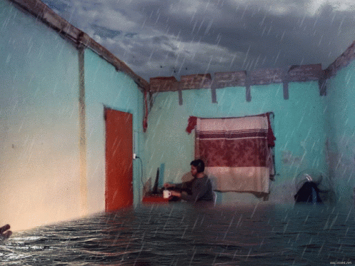 Man Sits in Flooded Room With Coffee
