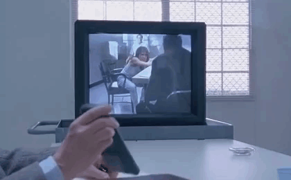 Man Sitting at Desk Holding Phone in Front of Computer