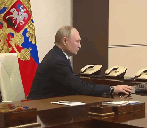 Man Sitting At Desk In Front Of Flag GIF