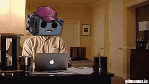 Man Sitting at Desk With Apple Laptop and Robot on Head