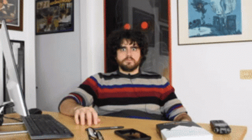 Man Sitting at Desk With Computer and Book