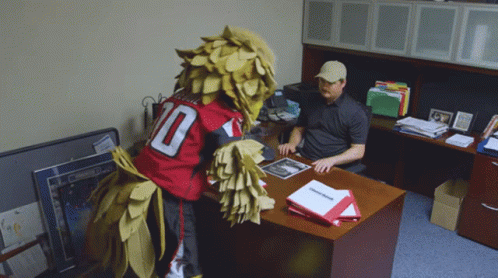 Man Sitting At Desk With Mascot In Number 10 Jersey GIF