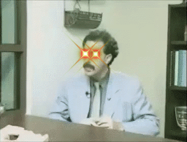 Man Sitting at Desk With Red Eyes and Mustache