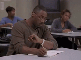 Man Sitting at Desk Writing in Notebook