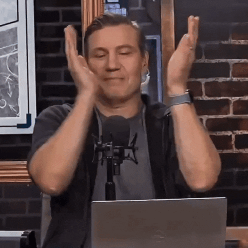 Man Sitting At Microphone With Hands In Air GIF