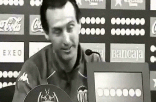 Man Sitting At Podium With Coca-Cola Bancaja Logos