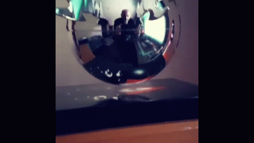 Man Sitting At Table In Front Of Floating Sculpture GIF