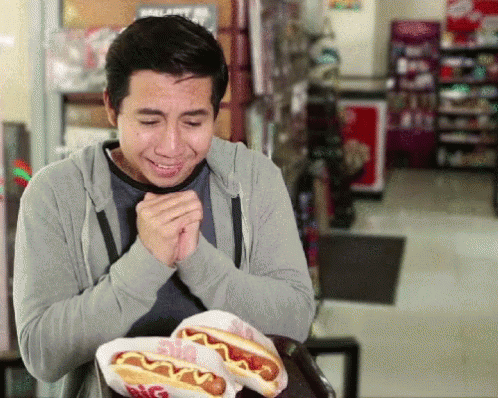 Man Sitting at Table With Big Hot Dogs