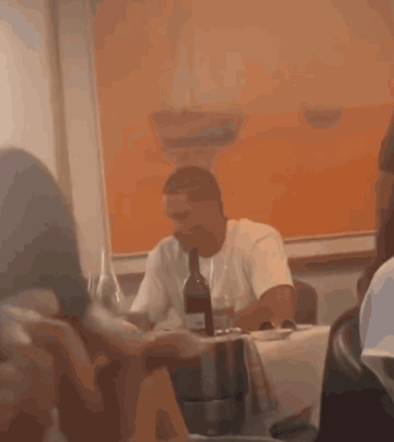 Man Sitting At Table With Bottle Of Wine GIF