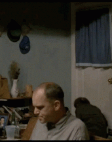 Man Sitting at Table With Hat on Wall