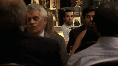 Man Sitting At Table With Lamp And Flowers GIF