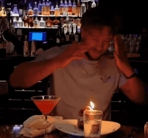 Man Sitting at Table With Martini and Candle