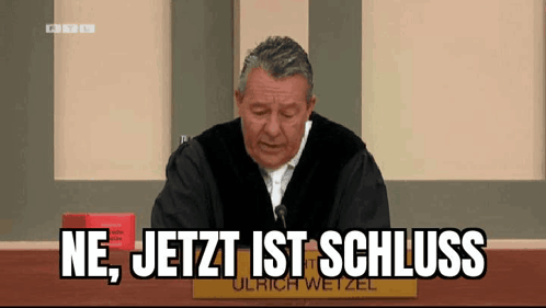 Man Sitting at Table With Schluss Words