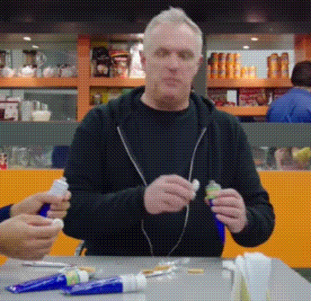 Man Sitting at Table With Toothpaste Tubes