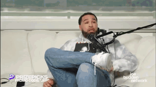 Man Sitting Crossed Legs in Front of Microphone
