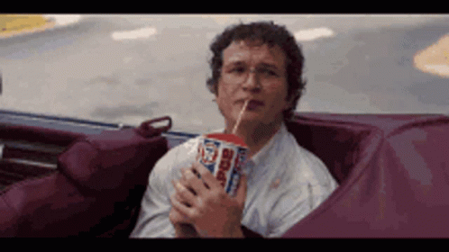 Man Sitting in Car Drinking Soda Through Straw