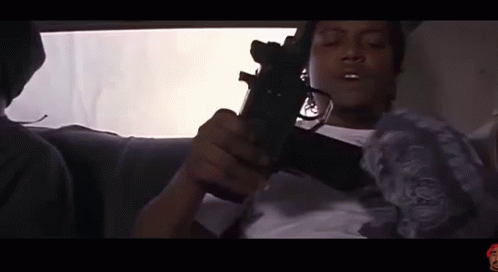 Man Sitting in Car Holding Gun