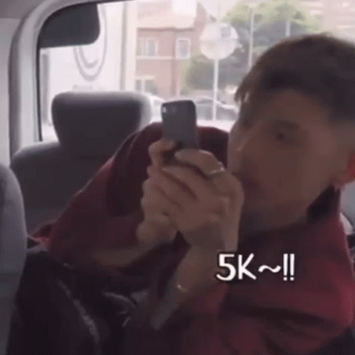 Man Sitting in Car Looking at Phone 5k
