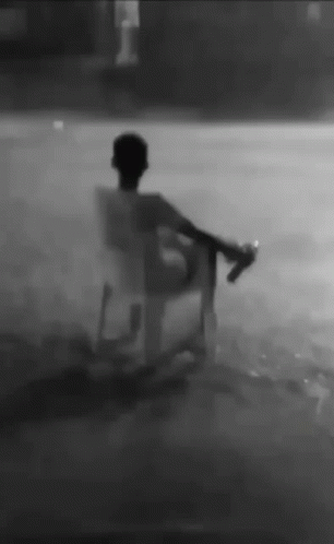 Man Sitting in Chair in Rain Holding Bottle