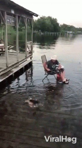 Man Sitting in Chair in Water Near Dock