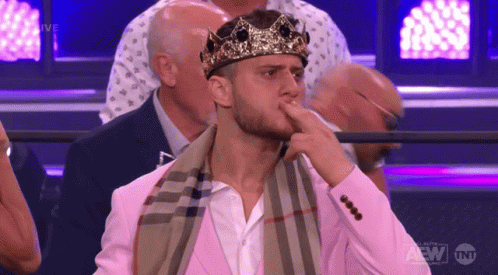 Man Sitting in Crown and Pink Suit at TNT Sign