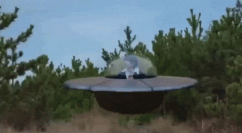 Man Sitting In Flying Saucer In Field GIF