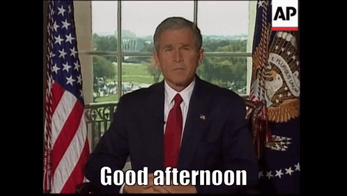 Man Sitting in Front of American Flag Saying Good Afternoon