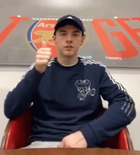 Man Sitting in Front of Arsenal Sign