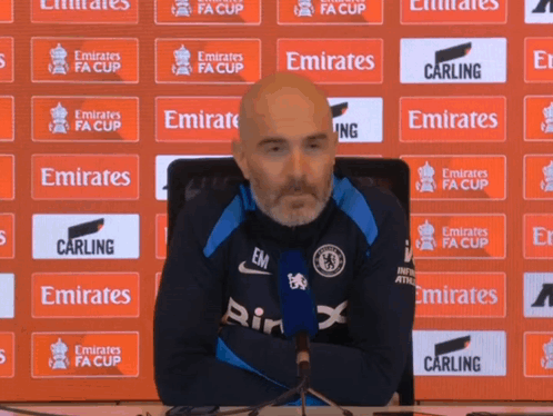 Man Sitting In Front Of Emirates FA Cup Banner GIF
