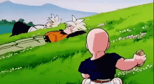 Man Sitting in Grass Looking at Lying Man