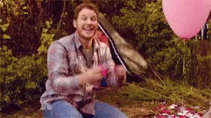 Man Sitting in Woods With Pink Balloons and Tent