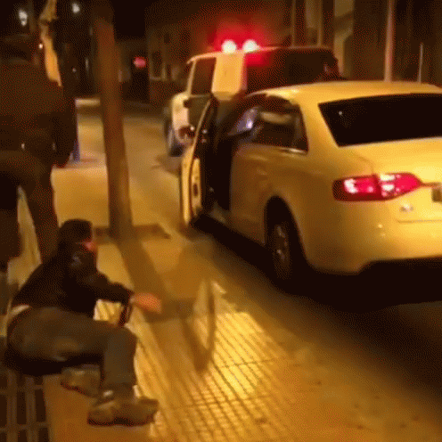 Man Sitting on Bench Next to White Car