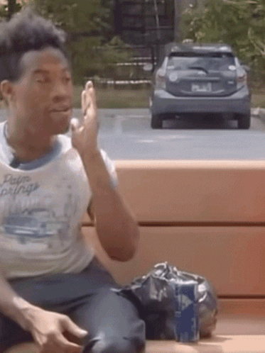 Man Sitting on Bench with Car in Background