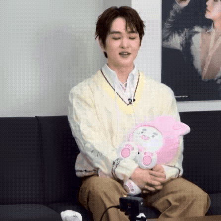 Man Sitting on Couch Holding Stuffed Animal