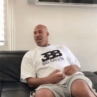 Man Sitting on Couch in Big Baller T-Shirt and Shorts