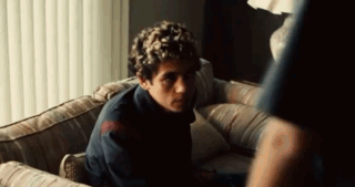 Man Sitting On Couch In Dark Room Looking At Something GIF