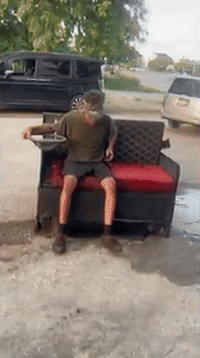 Man Sitting on Couch in Driveway with Van