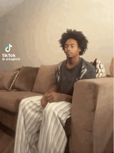 Man Sitting On Couch Legs Crossed Looking At Camera GIF
