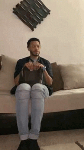 Man Sitting on Couch Petting Black Cat