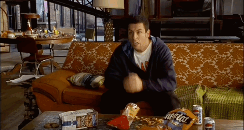 Man Sitting on Couch With Bag of Cheetos