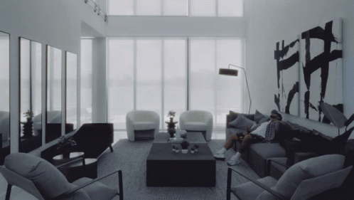 Man Sitting on Couch With Chairs and Coffee Table