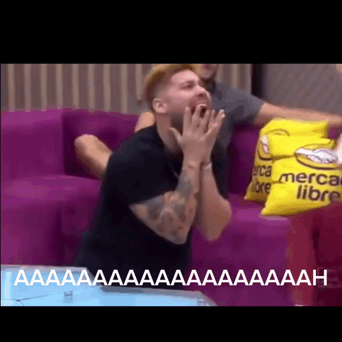 Man Sitting on Couch with Yellow Pillow Saying Mercado Libre