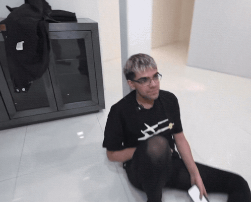 Man Sitting on Floor in Black Shirt Saying X