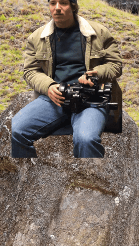 Man Sitting on Rock Holding Camera